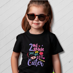 Child wearing a black t-shirt with colorful text on a light wooden background