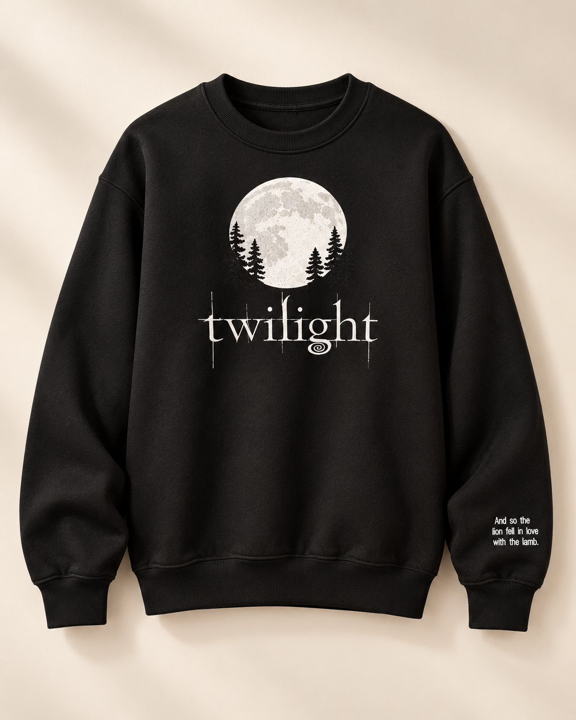 A black crewneck sweatshirt featuring a white graphic of a full moon, pine trees, and the word 'twilight' on the chest, with small white text on the right sleeve, displayed against a warm beige background.