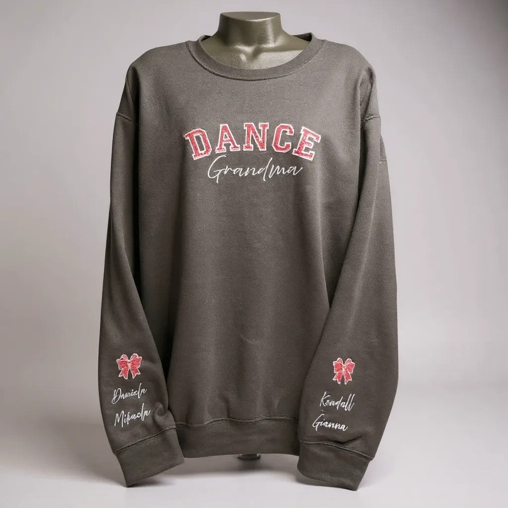 Black sweatshirt with 'DANCE Grandma' text on a mannequin against a gray background, with names on sleeve with a satin bow with glitter.