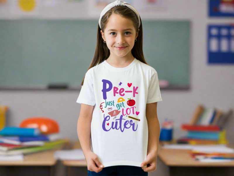 Young girl wearing a white t-shirt with colorful text against a blurred classroom background.