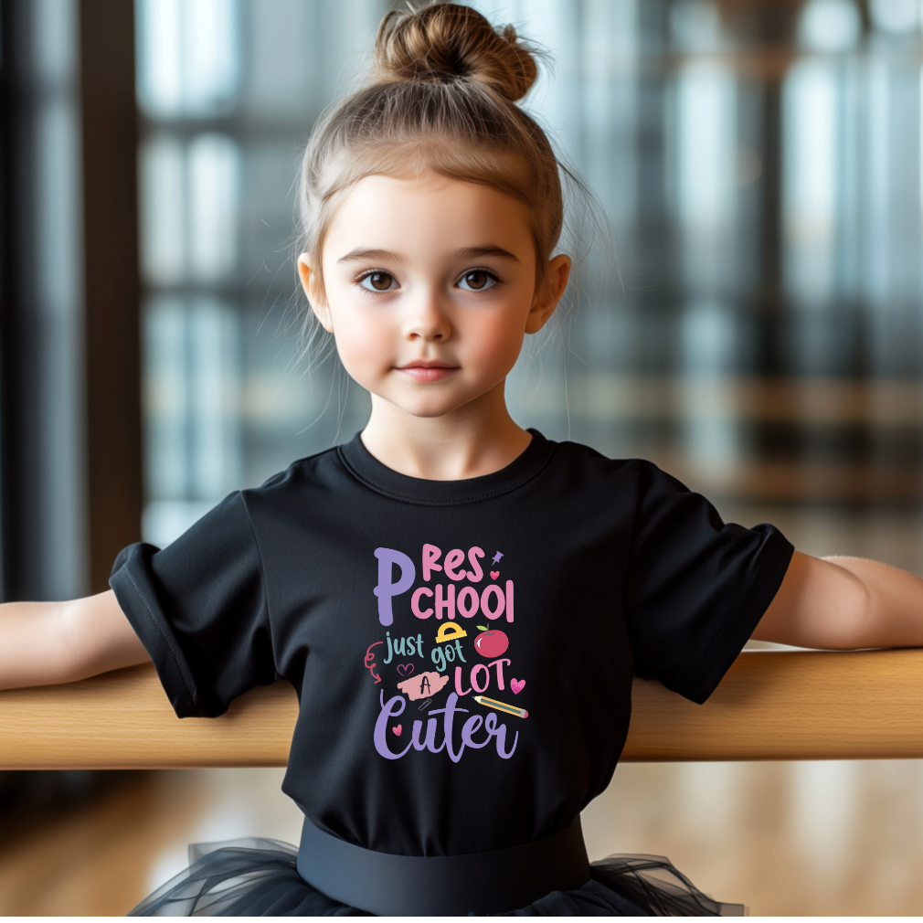 Young girl wearing a black t-shirt with colorful text, sitting on a wooden bench.