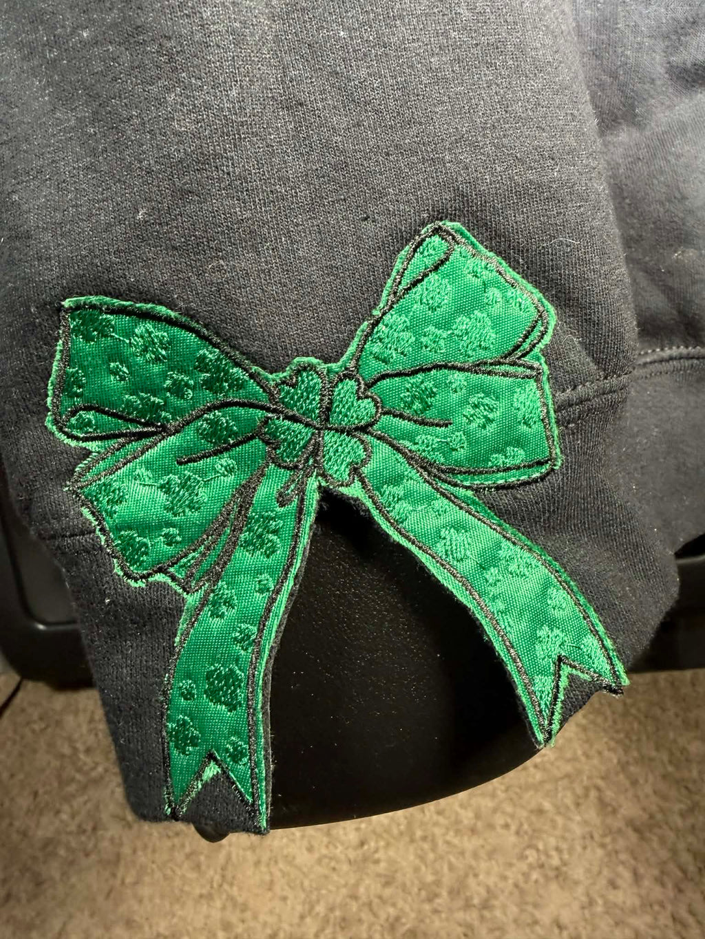 Green embroidered bow on a dark fabric background