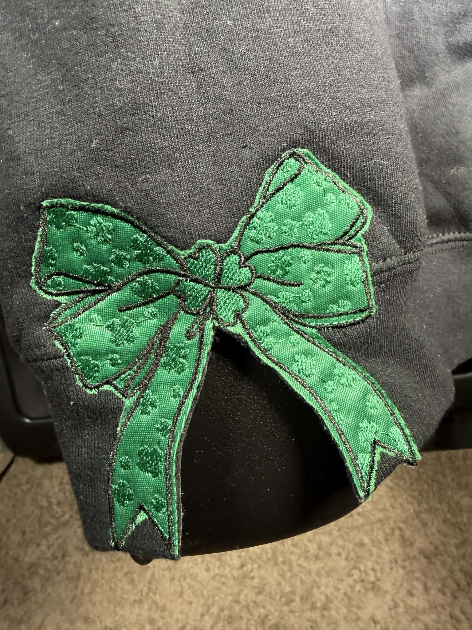 Green embroidered bow on a dark fabric background