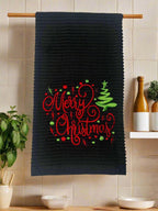 Black kitchen towels staged in kitchen with the words Merry Christmas with a Christmas tree and dots.