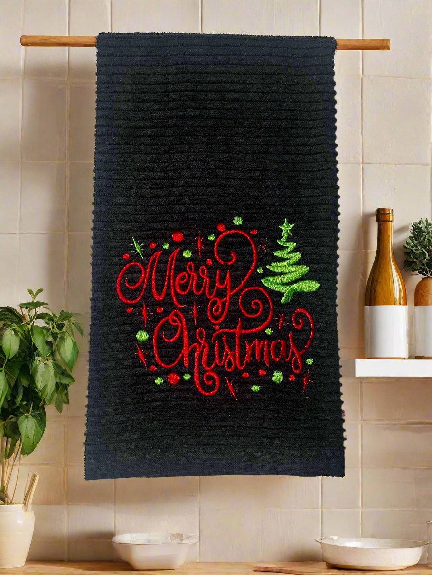 Black kitchen towels staged in kitchen with the words Merry Christmas with a Christmas tree and dots.
