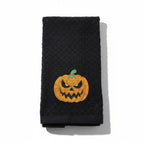 Black towel with a jack-o'-lantern design on a white background