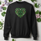 Black sweatshirt with a green floral heart design on a light background with flowers and leaves.