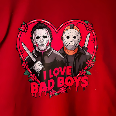 Close up of graphic on a long-sleeve red t-shirt with 'I Love Bad Boys' text and illustrations of two male figures resembling horror movie characters Michael Myers and Jason on the front with a blurred street background.