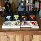 Collection of black and white t-shirts with colorful text and graphics on a wooden surface.