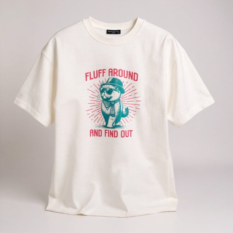 White t-shirt with a graphic of an otter wearing a hat and scarf, and text 'Fluff Around and Find Out' on a gray background.