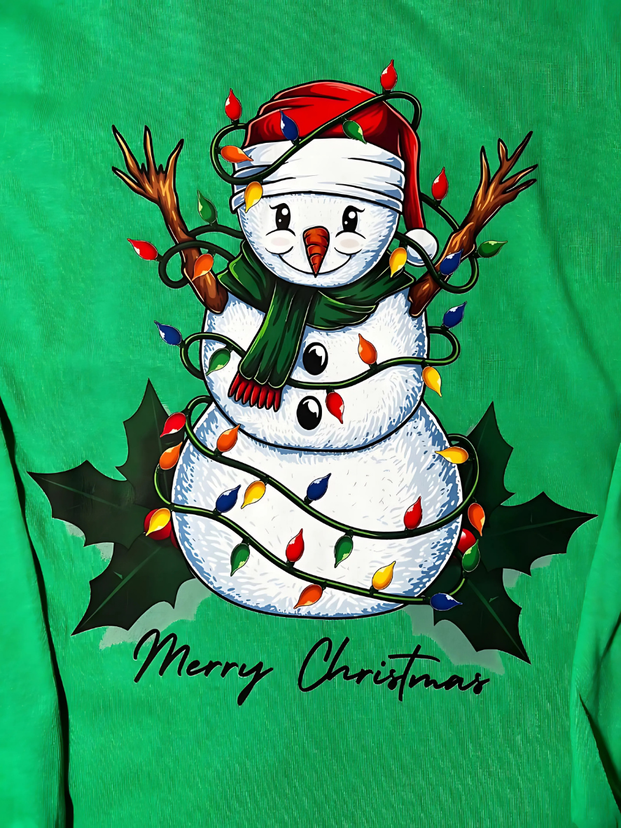 A green long-sleeve T-shirt with a graphic print of a snowman wrapped in Christmas lights and mistletoe with christmas lights in the background.