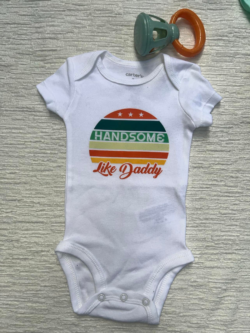 White baby onesie with a retro colorful graphic that says: "Handsome Like Daddy"