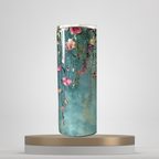 A set of three stainless steel tumblers with a floral design, featuring pink and white flowers and green leaves on a blue background, displayed on a wooden surface.