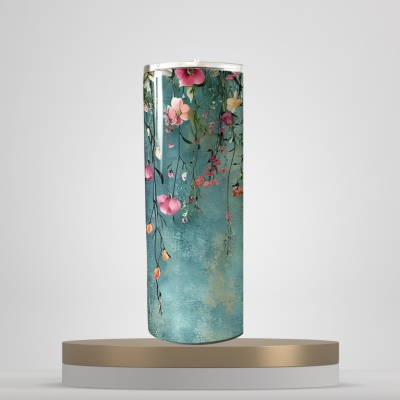 A set of three stainless steel tumblers with a floral design, featuring pink and white flowers and green leaves on a blue background, displayed on a wooden surface.
