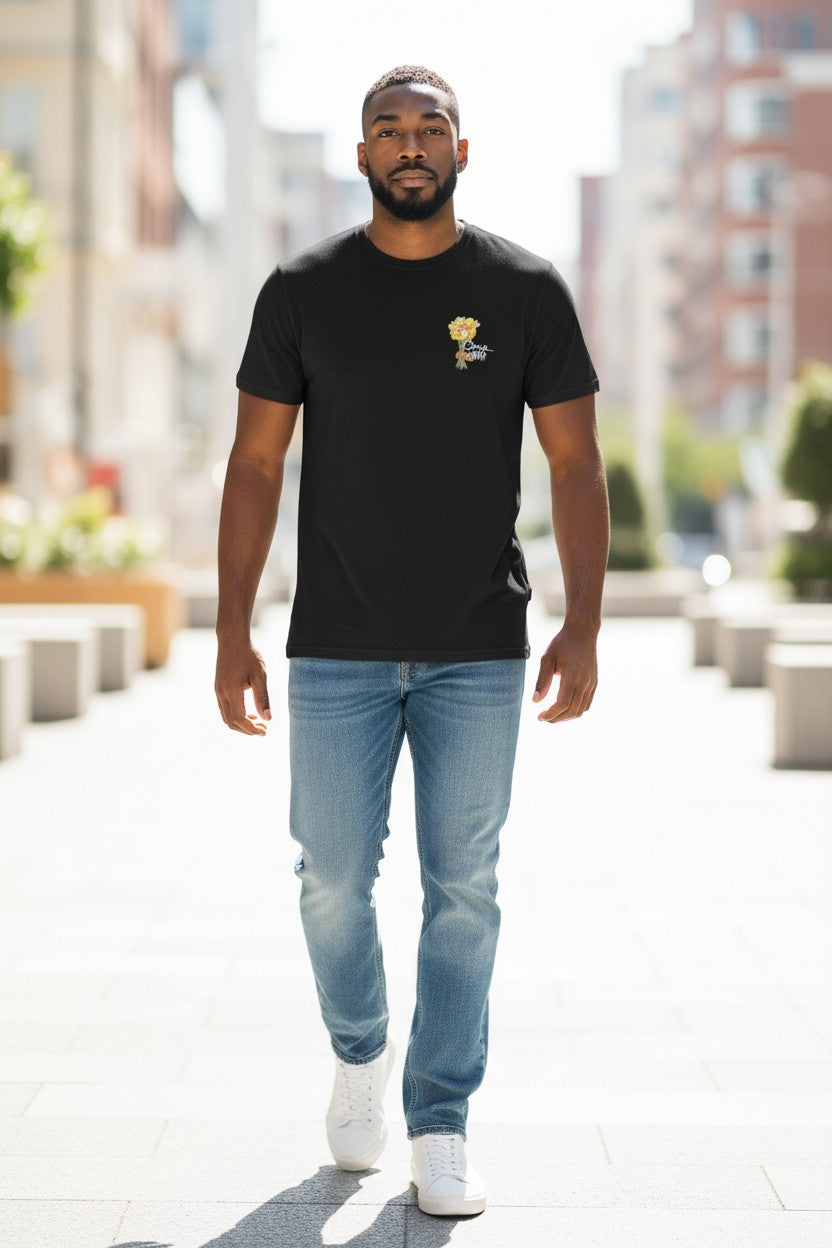 Man wearing a black t-shirt with a logo and light blue jeans walking on a city street.