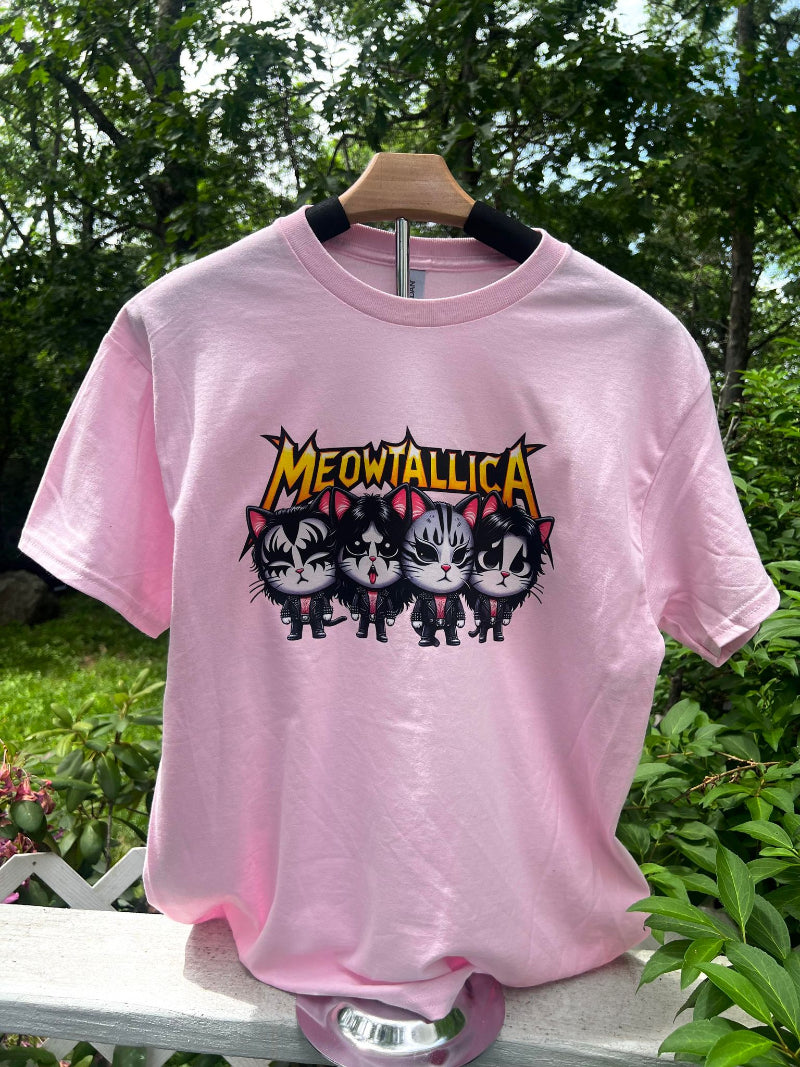 A pink graphic tee shirt featuring a black and white design of cat faces with the text 'MEOWTALLIA' in bold letters.