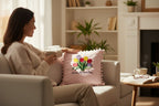 Woman sitting on a couch holding a cup, with a decorative pillow featuring flowers and 'Happy Mother's Day' text in a cozy living room.