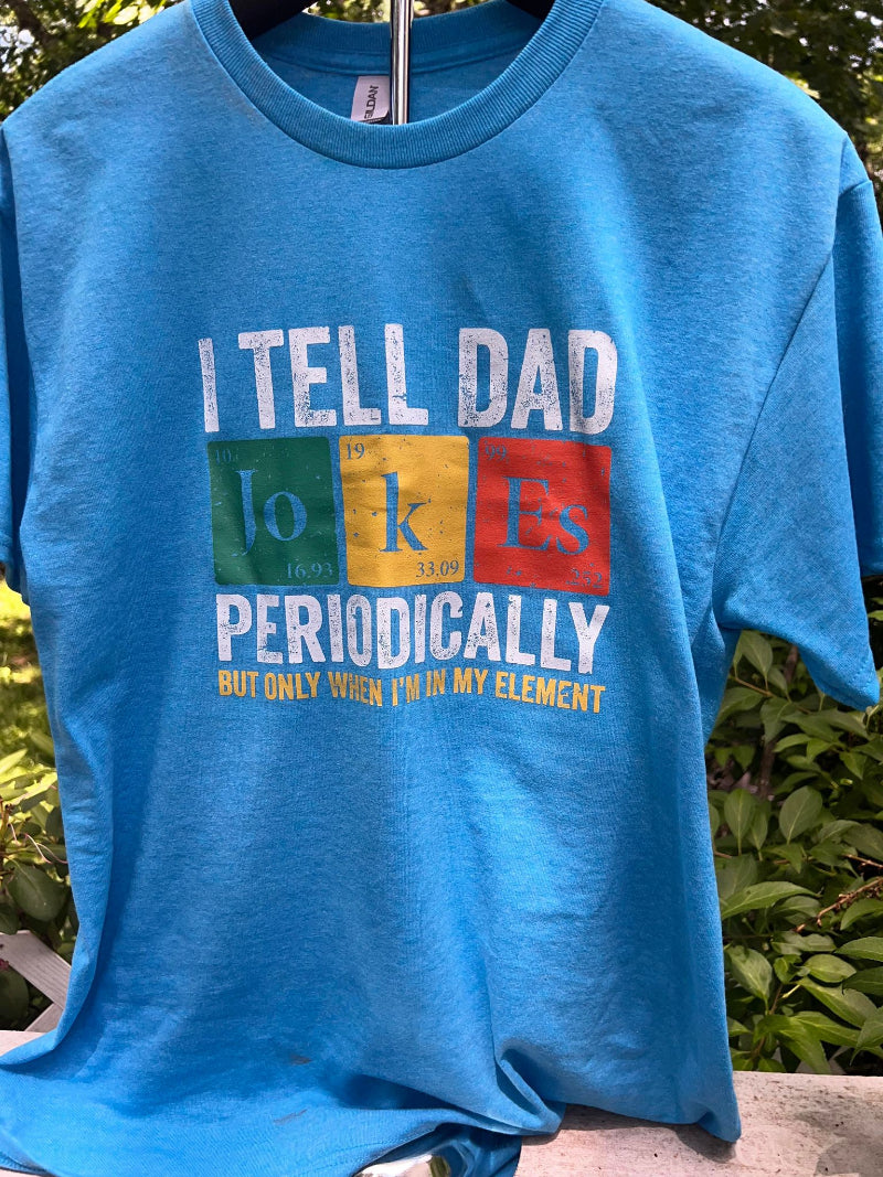 Chemistry-themed nerdy dad jokes graphic shirt on stand outdoors.