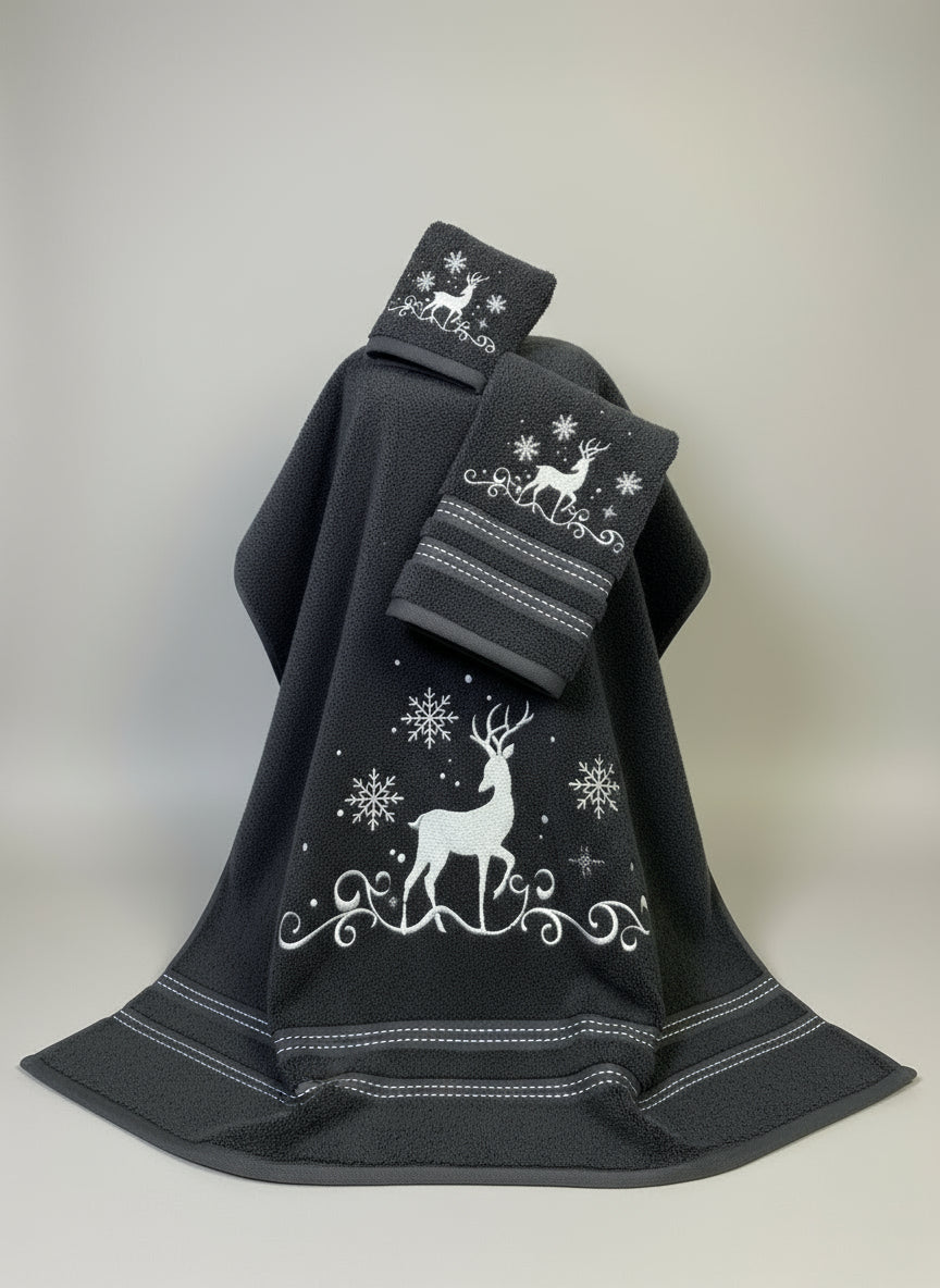 Black towel with white deer and snowflake designs on a gray surface