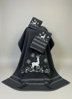 Black towel with white deer and snowflake designs on a gray surface