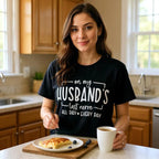 Woman in a kitchen wearing a black t-shirt with text, holding a mug and a plate of food.
