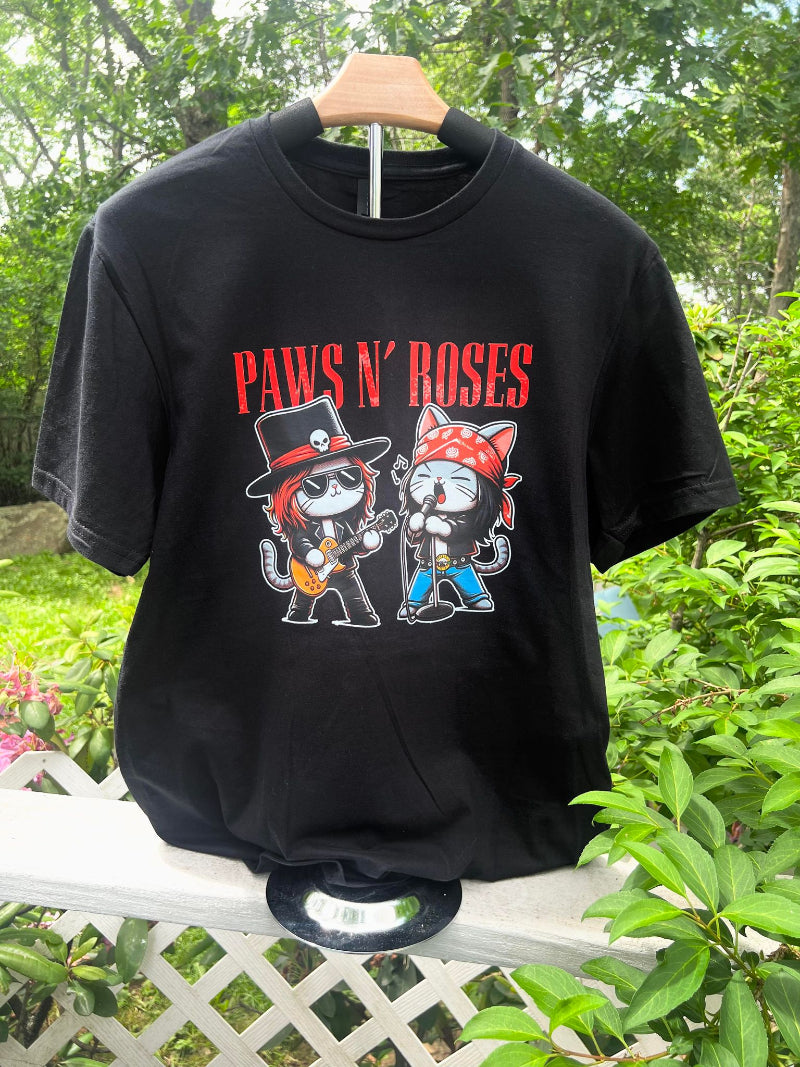 A black vintage graphic tee with a design of two cartoon cats wearing band hats and playing guitars, and the text 'PAWS N' ROSES' above them.