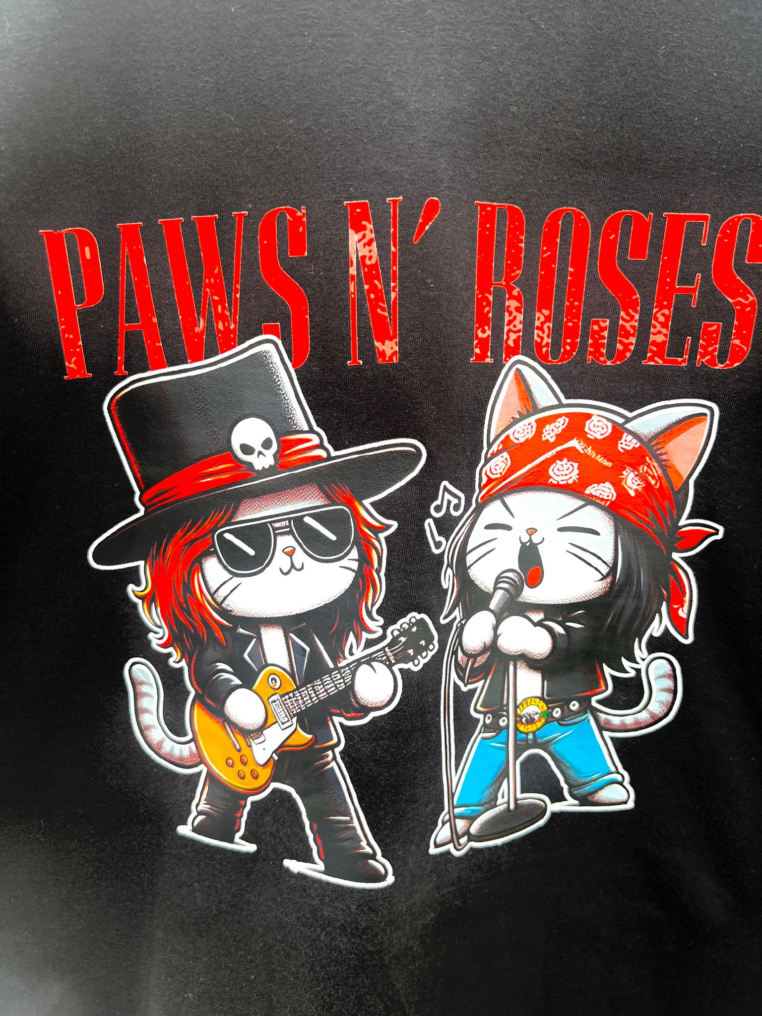 Close-up of graphic of cat musicians with guitars and bandanas on Paws N’ Roses tee.