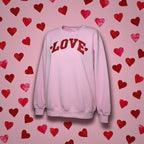 Pink sweatshirt with 'LOVE' text on a pink background with red hearts