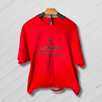 Red shirt with a cross design and 'REDEEMED' text on a wooden hanger against a light wooden background