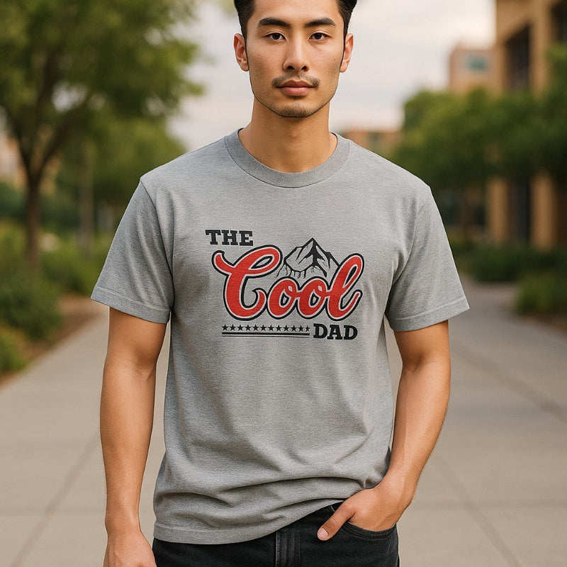 Man wearing a gray t-shirt with 'The Cool Dad' print outdoors.