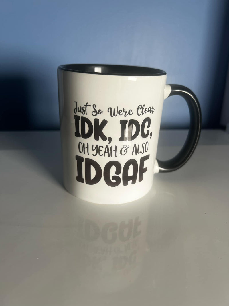 A white ceramic mug with black text that reads 'Just so we’re clear: IDK, IDC... oh yeah, & also IDGAF'.