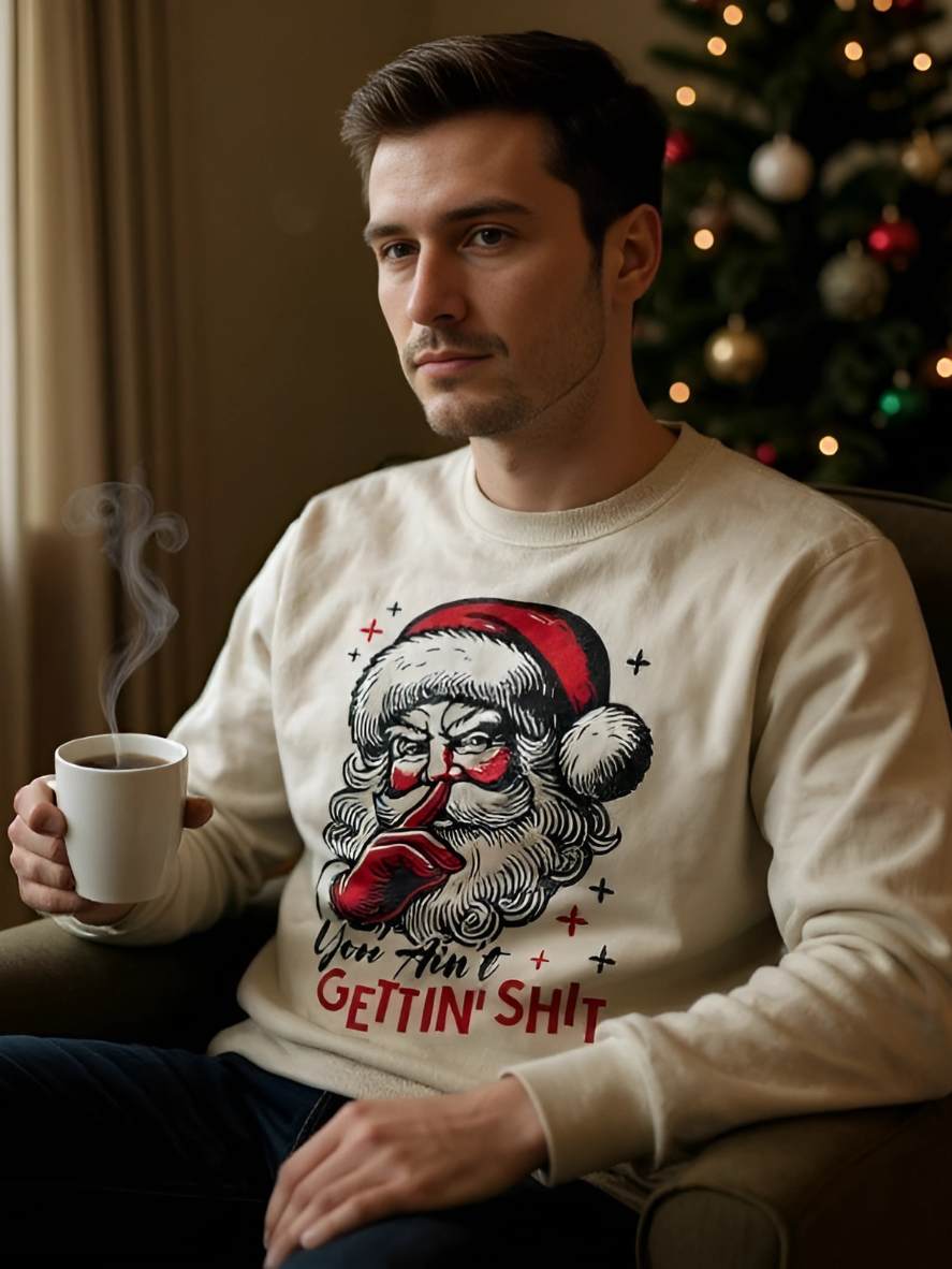 Man wearing a Christmas-themed sweater with Santa Claus holding a coffee cup, sitting in a room with a decorated tree.
