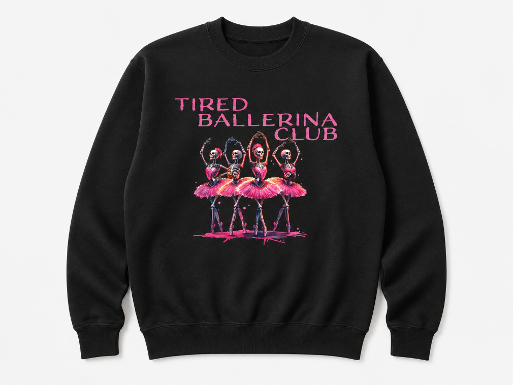 A black crewneck sweatshirt featuring a graphic print of four ballerina skeletons in pink tutus with the text 'TIRED BALLERINA CLUB' in pink above them, displayed on a light gray background.