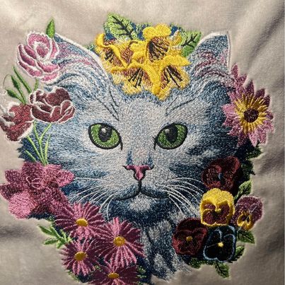 Close up of embroidered pillow cover featuring a cat with flowers design, completed with a pillow insert.
