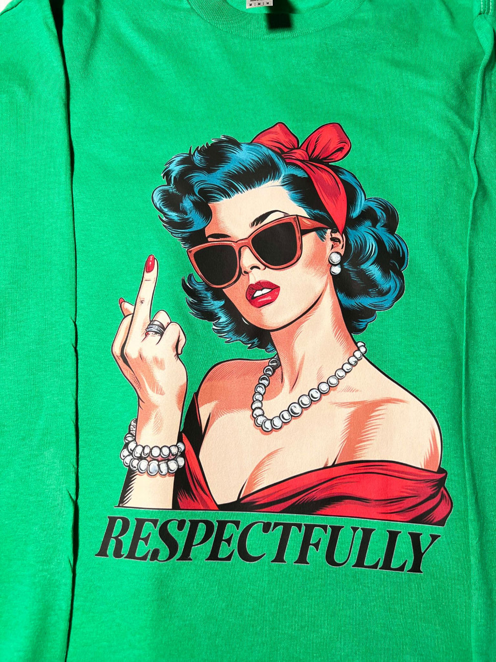 close up of a green long sleeve tee with a graphic of a woman in sunglasses giving a peace sign and the text 'RESPECTFULLY' below it.