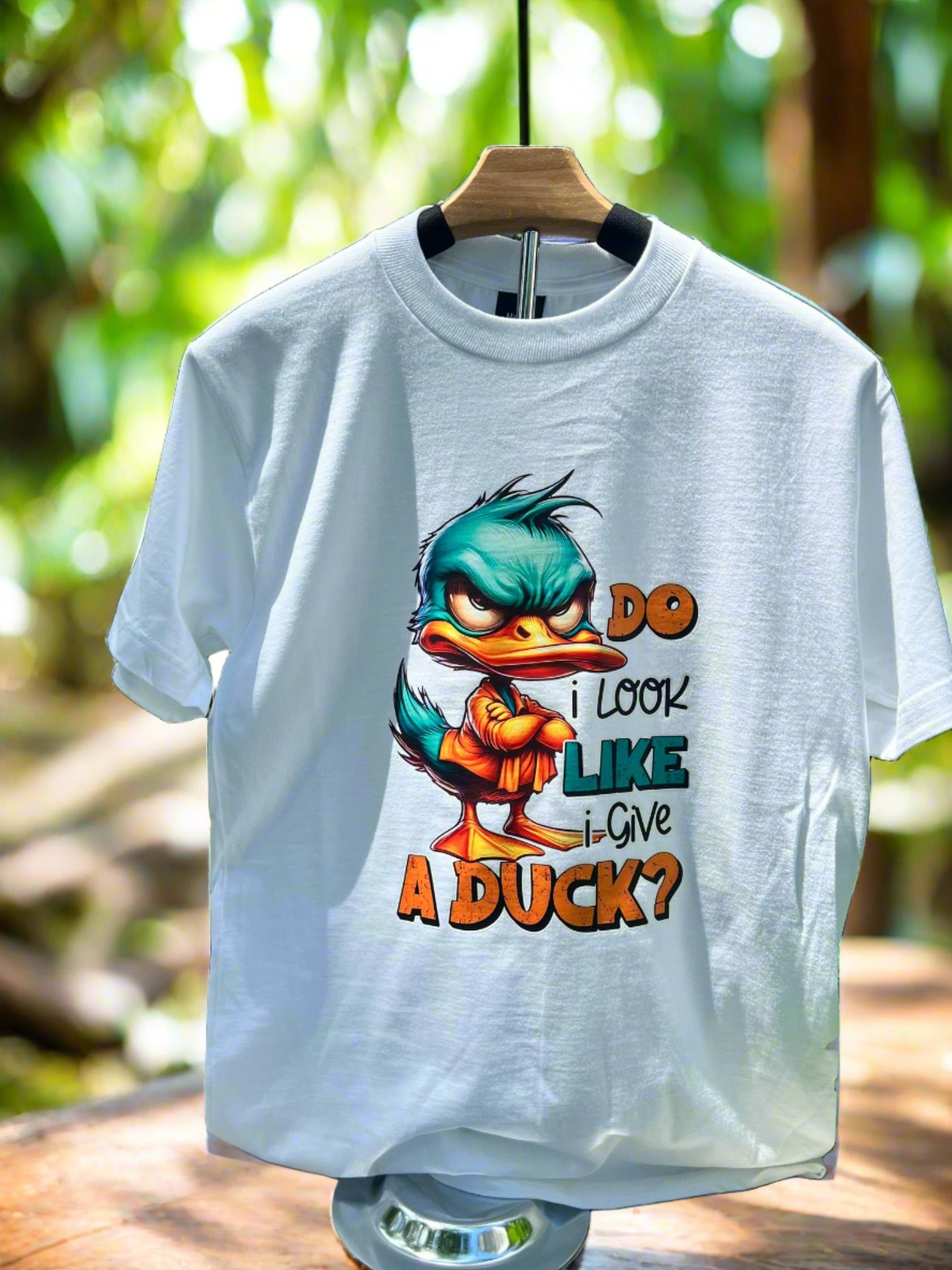 Funny duck graphic tee hanging on hanger in natural outdoor light.