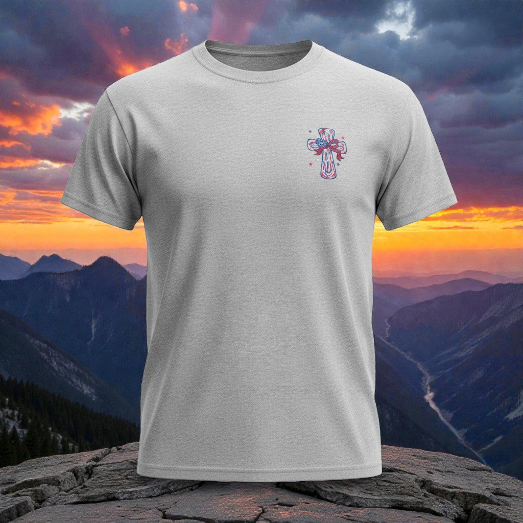 Faith based USA shirt with cross front design red white blue Christian apparel with mountain sunset background.