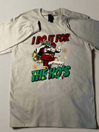 A cream-colored t-shirt with a graphic print of Santa Claus and the text 'I Do It for the Ho's' surrounded by Christmas lights.
