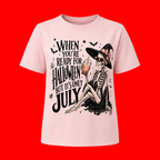 A light pink short-sleeve t-shirt with a Halloween graphic on the front, featuring a skeleton in a witch hat holding an iced drink next to the text 'WHEN YOU'RE READY FOR HALLOWEEN BUT IT'S ONLY JULY'.