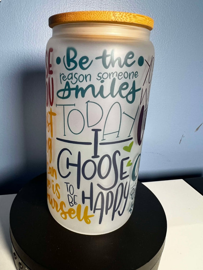 A frosted glass motivational cup with colorful text and designs, displaying affirmations such as 'You are worthy of love' and 'You are loved', with a bamboo lid on top and a straw included.
