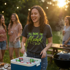 Woman in a 'I'll Bring the Alcohol' shirt at a barbecue with friends in the background.