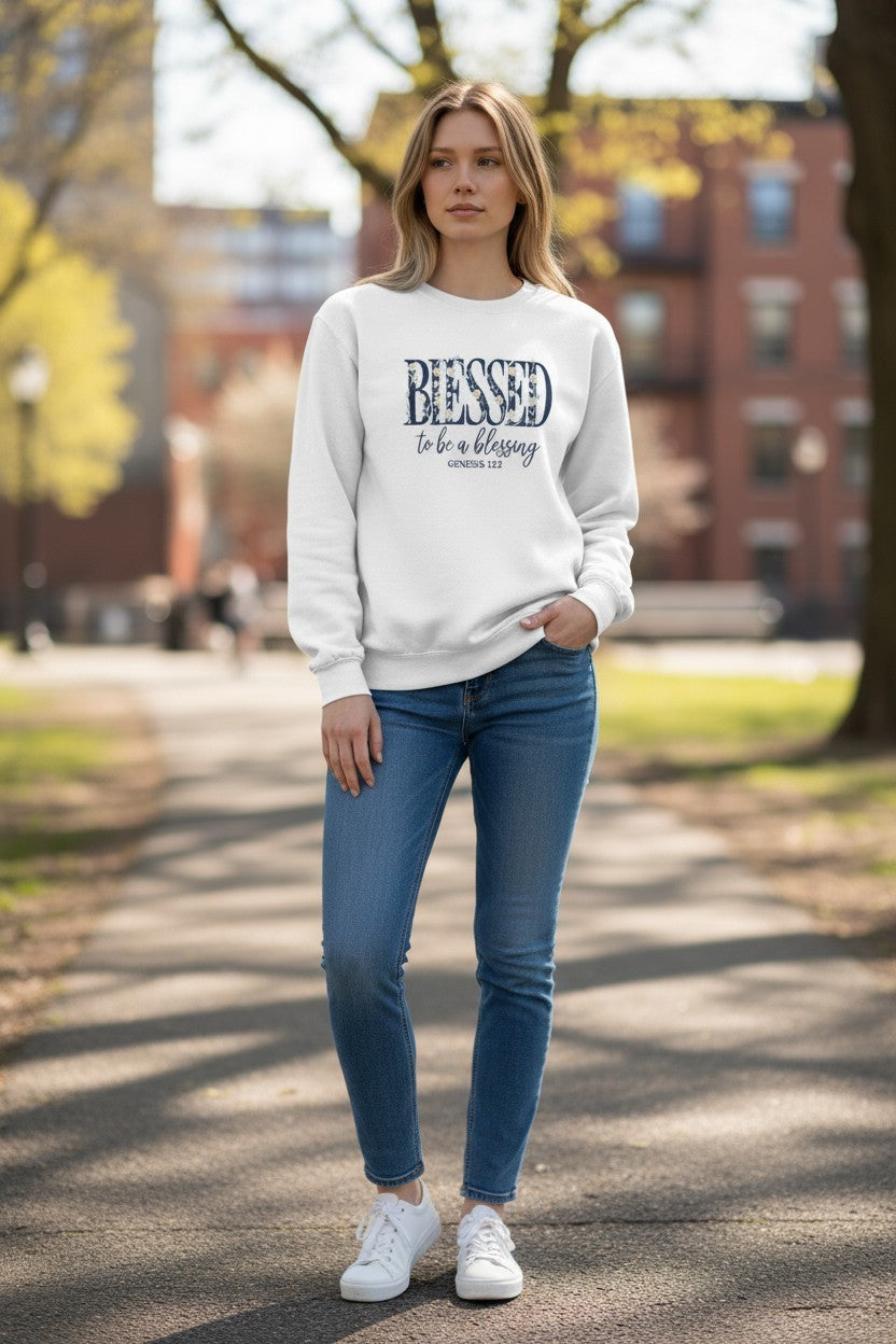 Woman wearing a white sweatshirt with text and blue jeans standing outdoors.