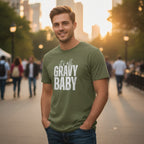 Man wearing a green t-shirt with 'It's all gravy baby' text in an urban setting.