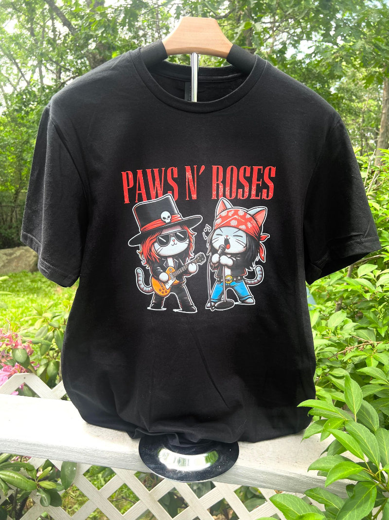 Black Paws N’ Roses graphic t-shirt hanging outdoors on wooden hanger.