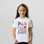 Young girl wearing a white t-shirt with colorful text on a light wooden floor.