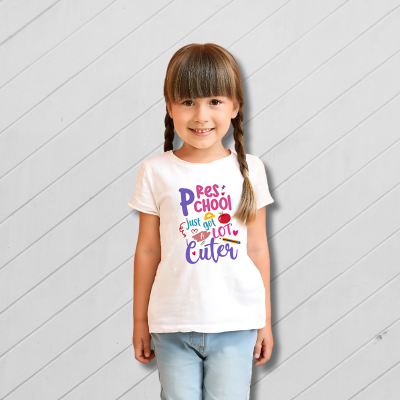 Young girl wearing a white t-shirt with colorful text on a light wooden background