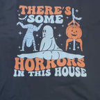 Video of a Black Gildan Ultra Cotton Halloween shirt with funny retro graphic of ghost, mummy, and pumpkin with text “There’s Some Horrors in This House"