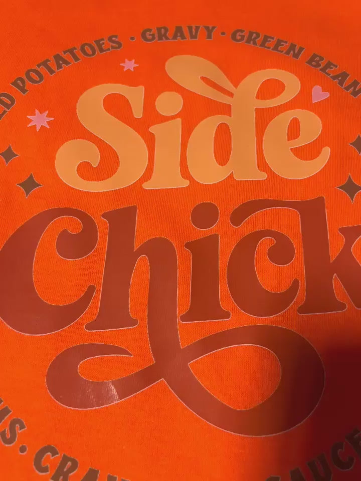 video showcase of orange Side Chick Thanksgiving Tee with bold Side Chick foodie graphic, highlighting comfort and holiday humor
