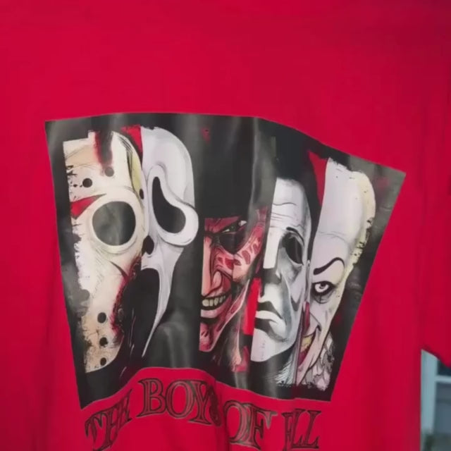 A red short-sleeved t-shirt with a graphic print featuring various horror movie characters in black masks and costumes, with the text 'Halloween Collection: The Boys of Fall'.