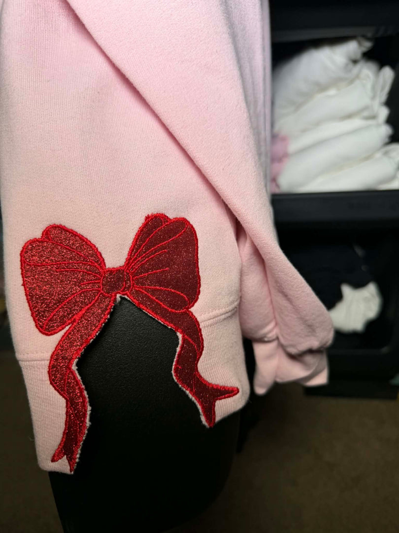 Pink garment with a red bow embroidered on a pink sweatshirt 